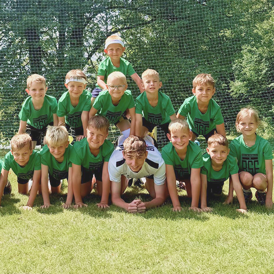 Děti na kempu Bav se fotbalem pózují na fotku